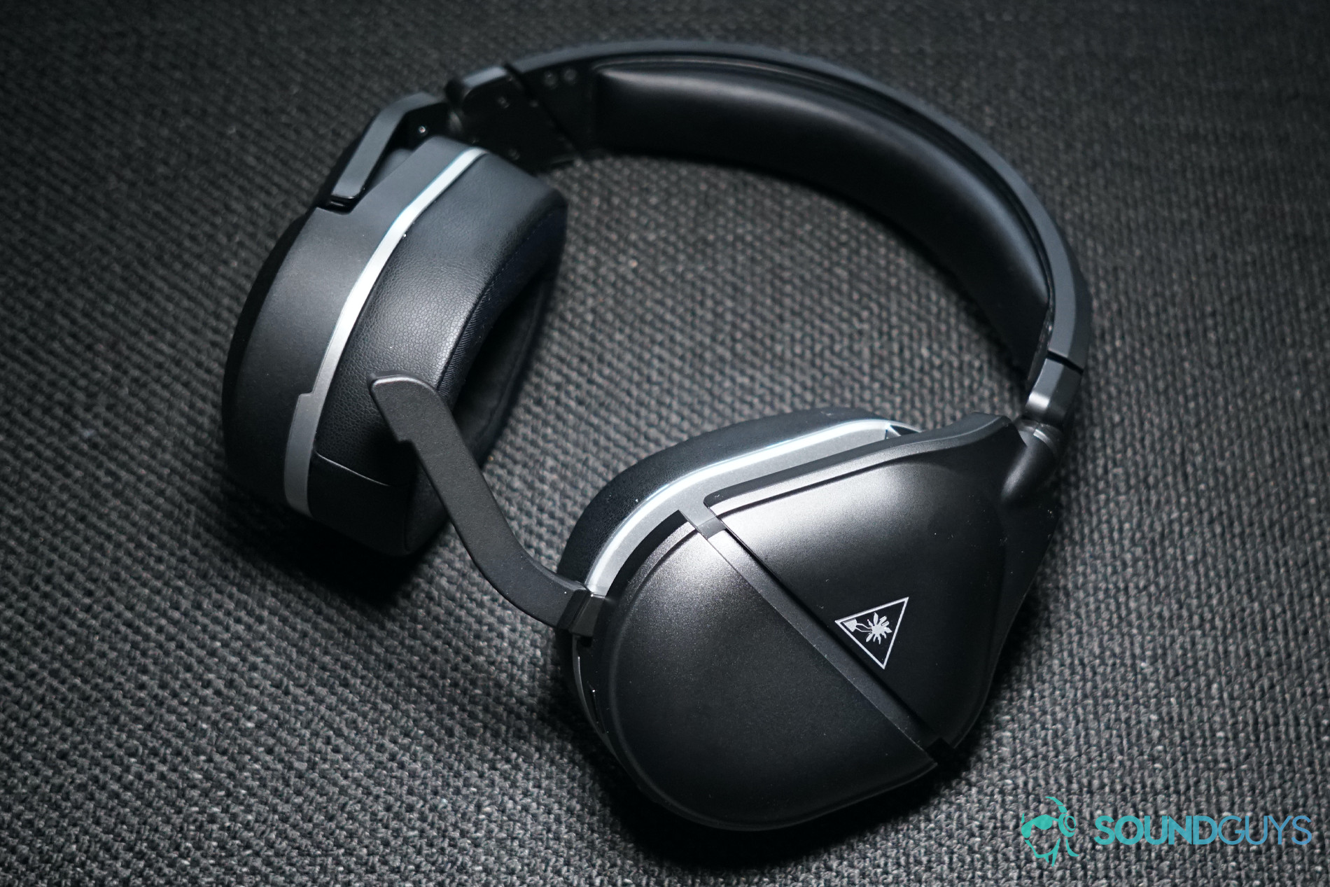 The Turtle Beach Stealth 700 Gen 2 sits on a fabric surface with its attached mic unfolded.