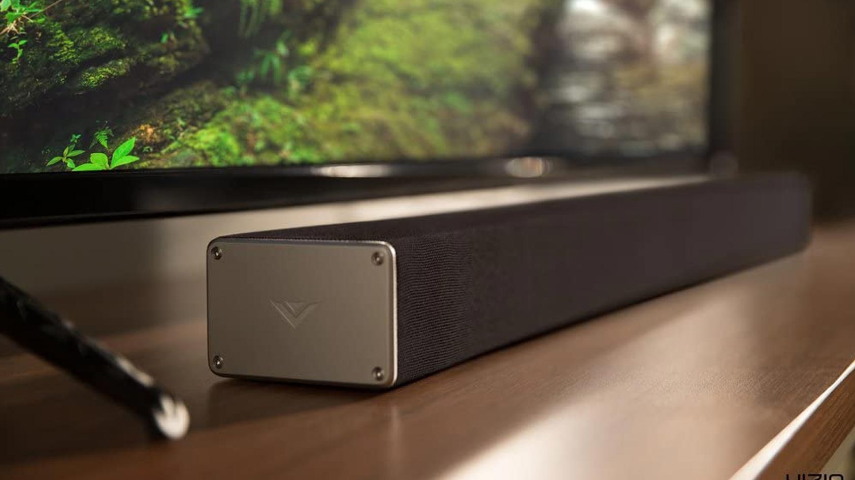 The Vizio SB3651-F6 home theater sound bar system on a wooden table in front of a television.