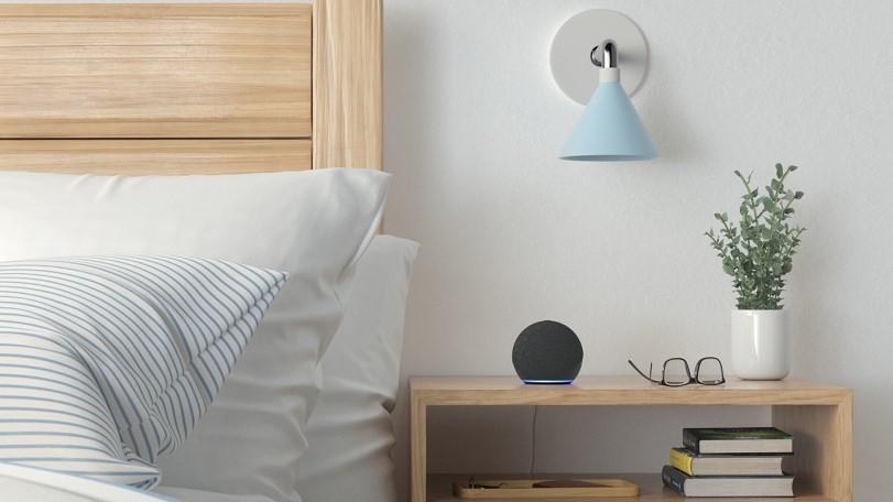 A picture of the Amazon Echo (4th Gen) in black on a bedroom nightstand.