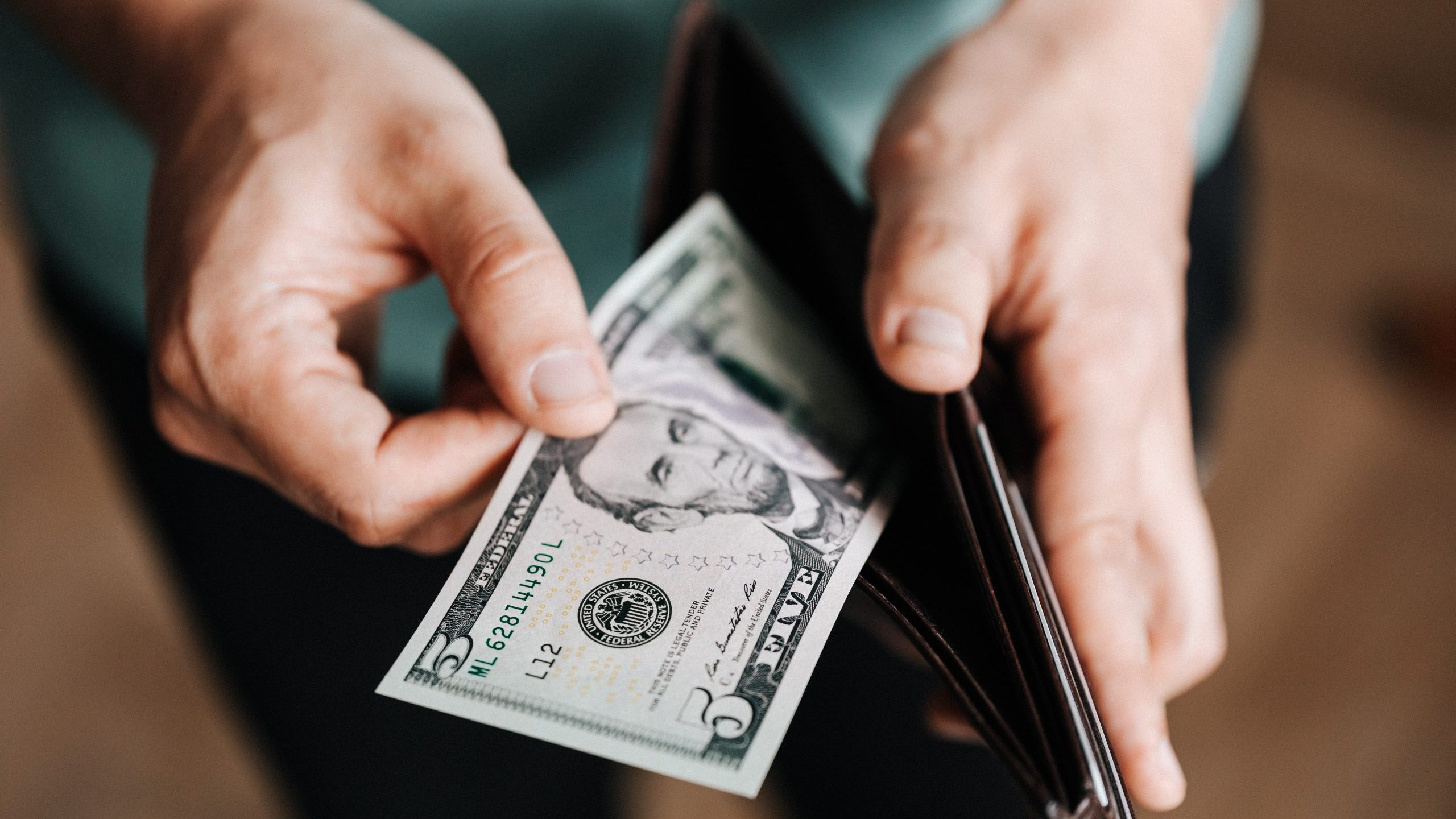 pexels-karolina-grabowska-4386421 A photo of a man removing money from a leather bi-fold wallet.