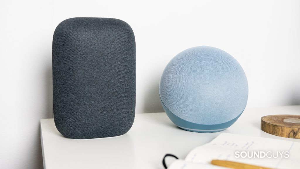Amazon Echo 4th gen next to Google Nest Audio and a notebook on a white desk.