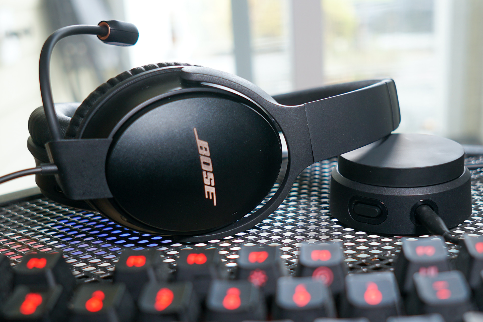 Bose QuietComfort 35 II Keyboard module shot The Bose QuietComfort 35 II Gaming Headset lays on a metal table next to its volume dial and a Logitech G413 Carbon mechanical gaming keyboard.