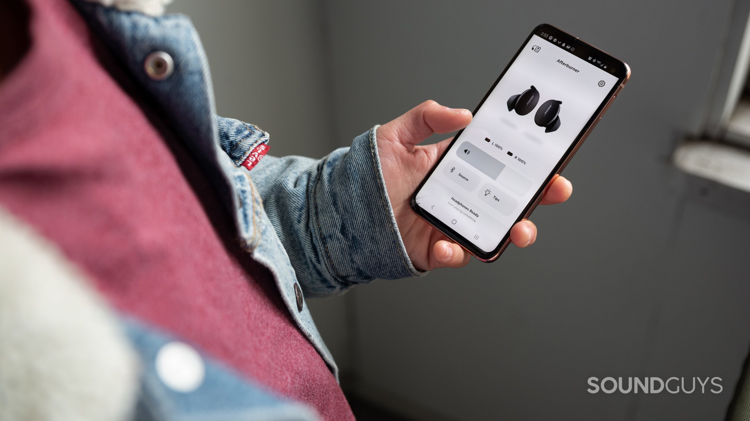 A woman uses the The Bose Sport Earbuds true wireless workout earbuds' mobile app, the Bose Music app.