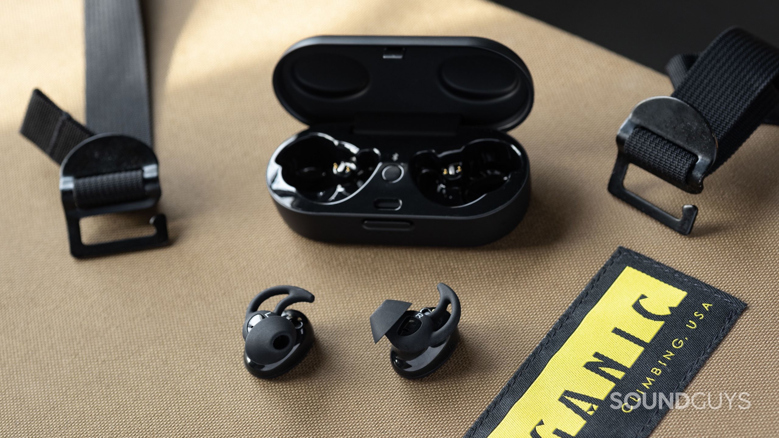 The Bose Sport Earbuds true wireless workout earbuds outside of the open charging case; the earbuds are facing belly-up so the StayHear Max ear tips are in full view.