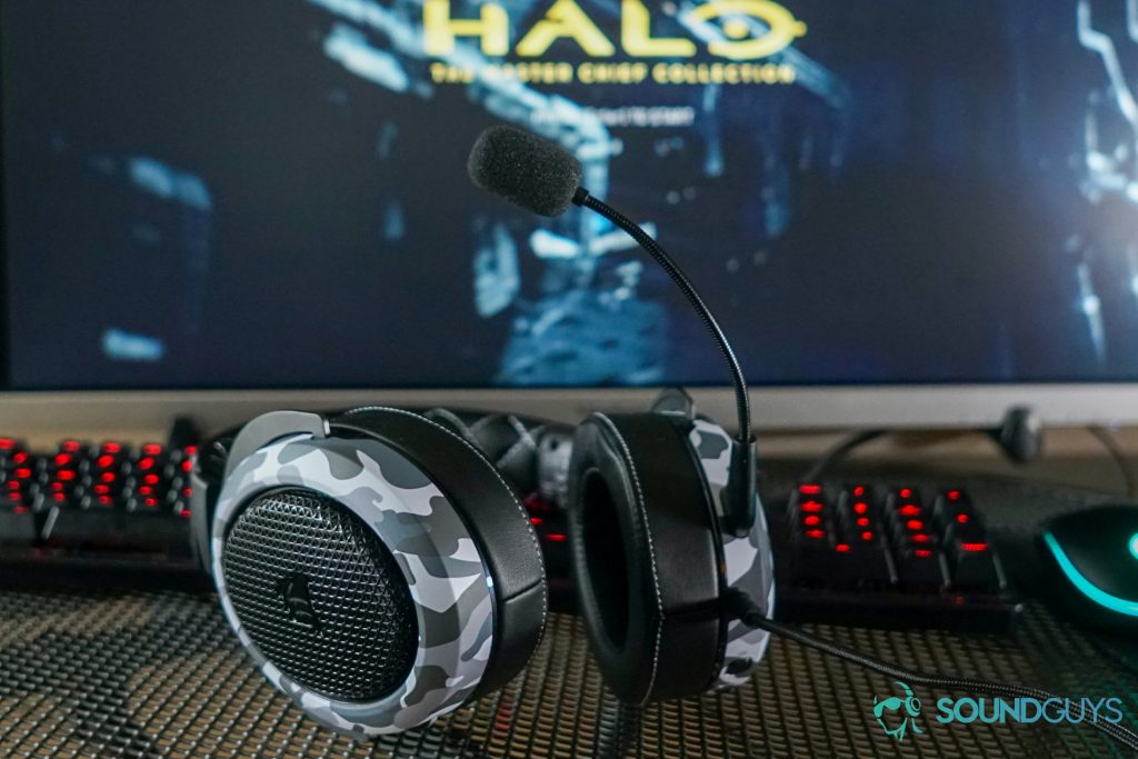 The Corsair HS60 Haptic lays on a desk in front of a gaming keyboard and mouse and a PC running Halo: the Master Chief Collection