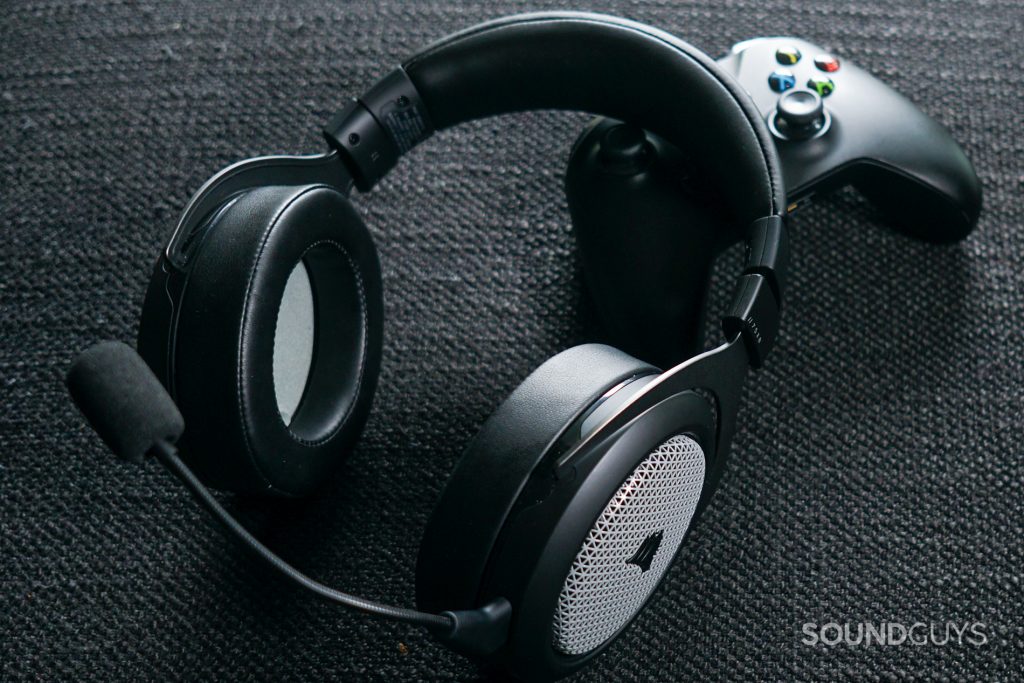 The Corsair HS75 XB Wireless lays on top of an Xbox One controller, on a fabric surface.
