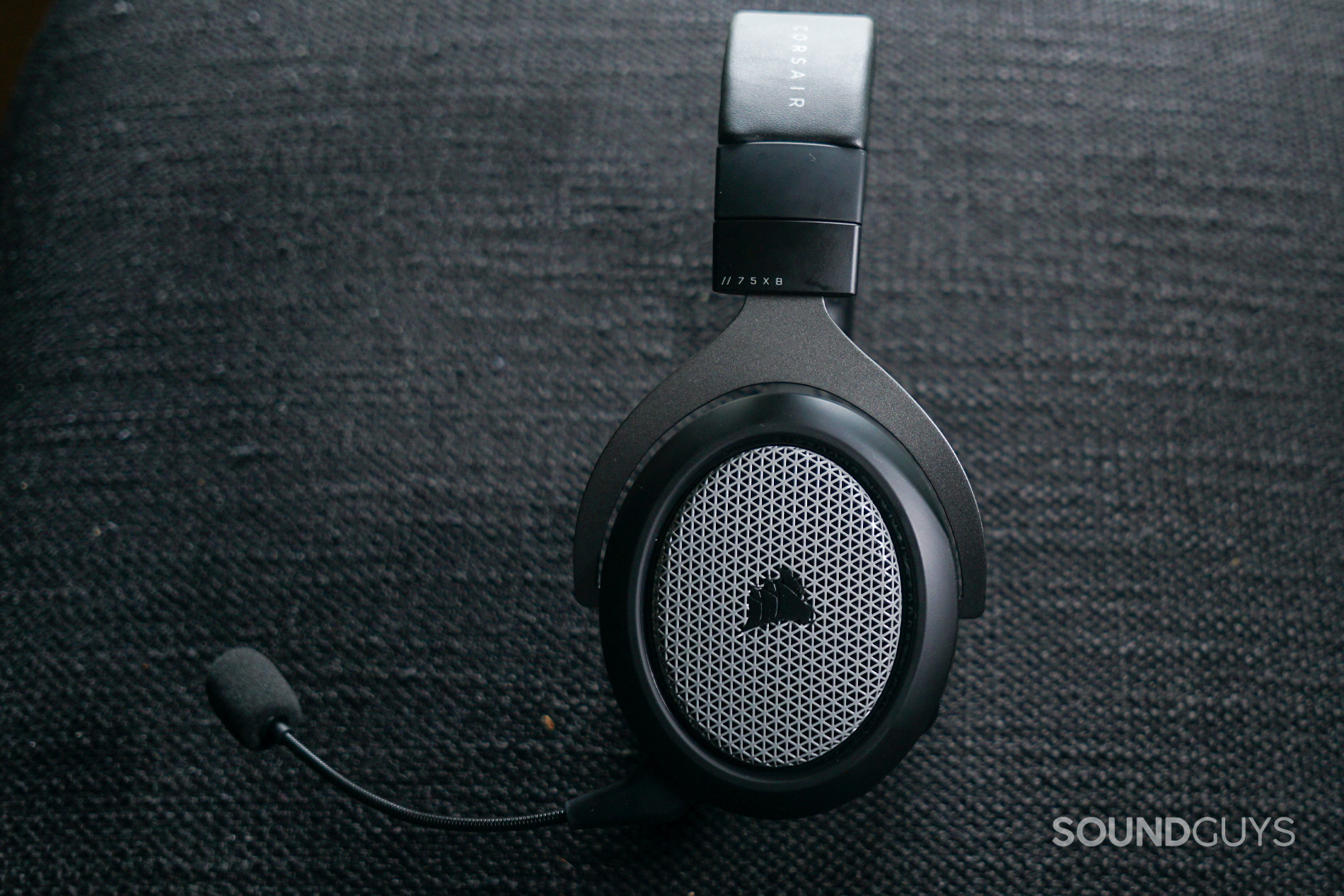 The Corsair HS75 XB Wireless lays on its side on a fabric surface