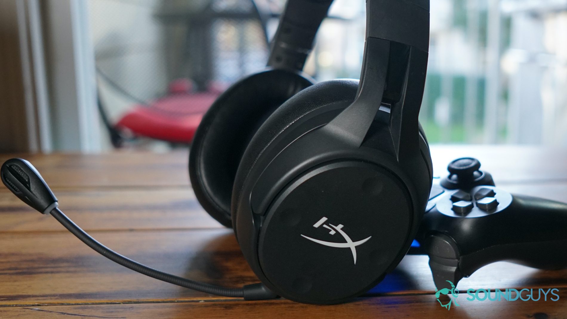 A picture of the HyperX Cloud Flight S leans on a Playstation 4 controller on a wooden table.