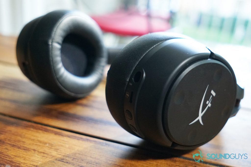 The HyperX Cloud Flight S sits on a wooden table by a window with a chair on the other side of it.