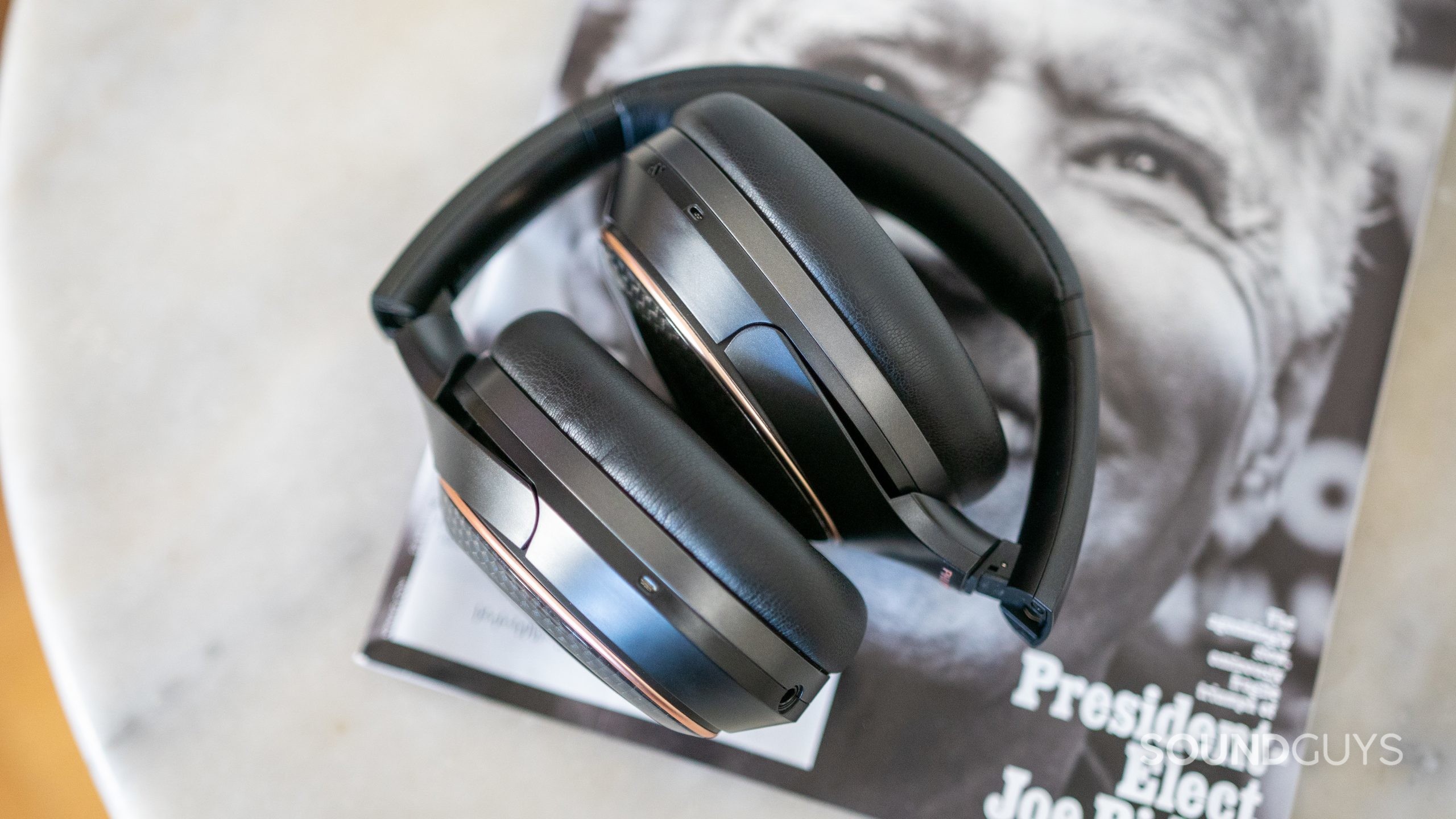 Phiaton 900 Legacy headphones folded on top of magazine on marble table.