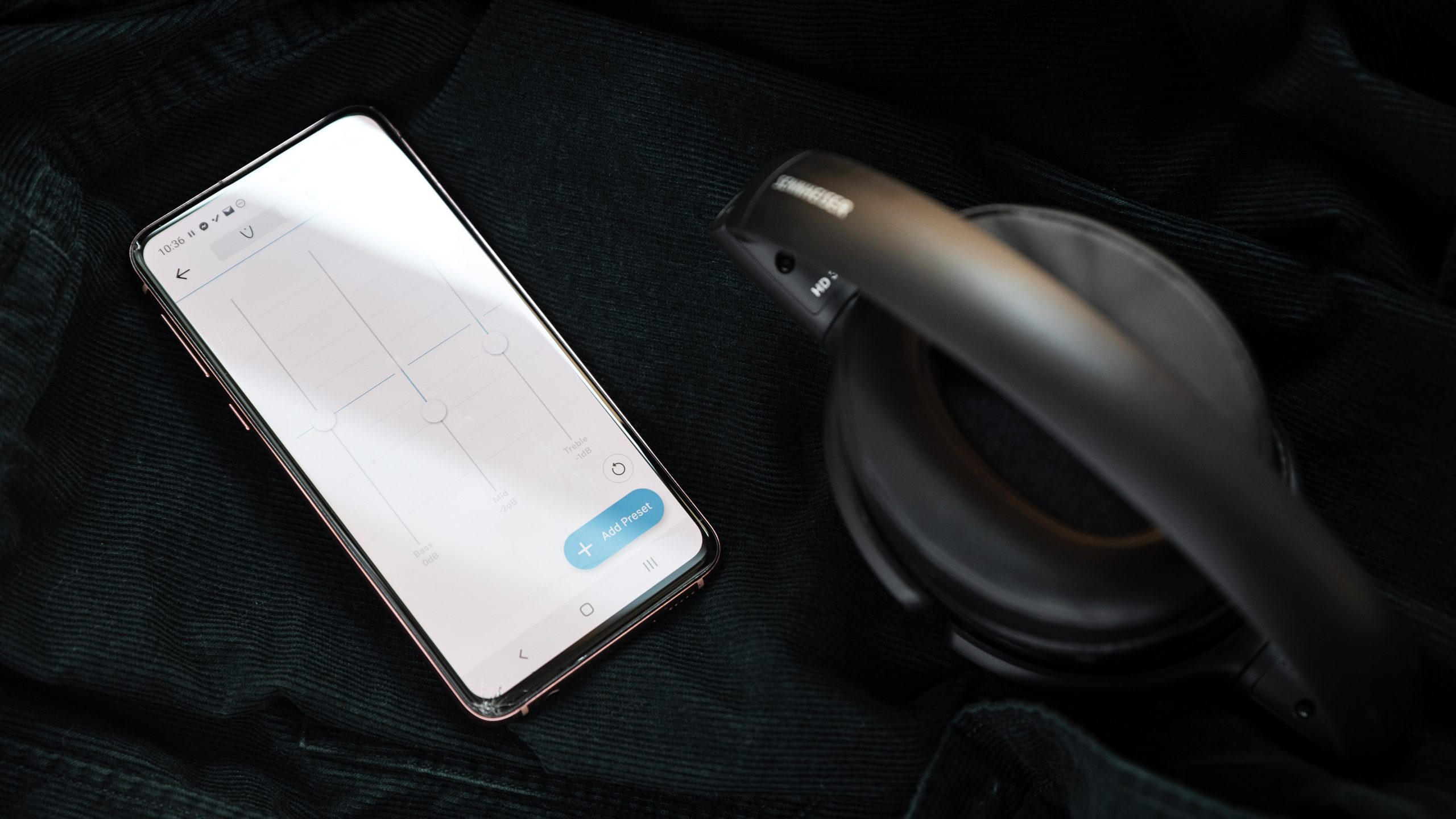 The Sennheiser HD 350BT Bluetooth headphones folded next to a Samsung Galaxy S10e with the Sennheiser Smart Control app with the custom EQ module open.