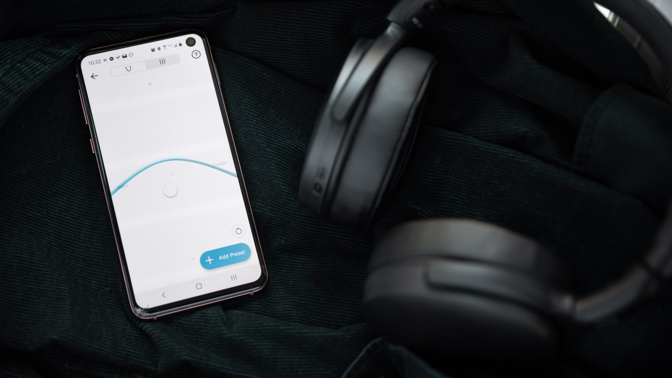 The Sennheiser HD 350BT Bluetooth headphones folded next to a Samsung Galaxy S10e with the Sennheiser Smart Control app with the visual custom EQ module open.