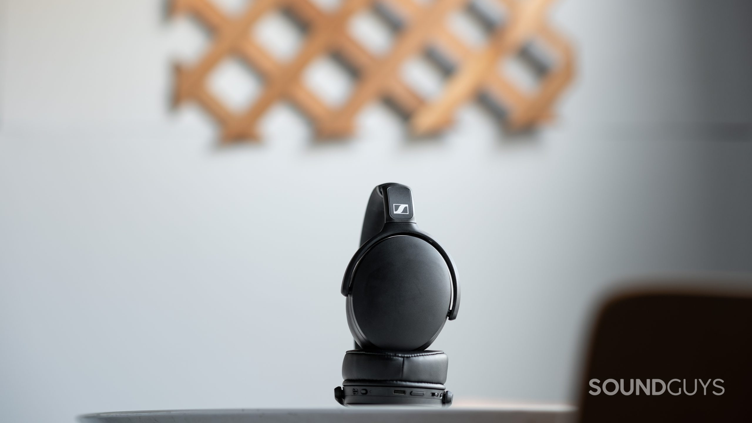 The Sennheiser HD 350BT Bluetooth headphones folded slightly on a table in front of an off-white wall.