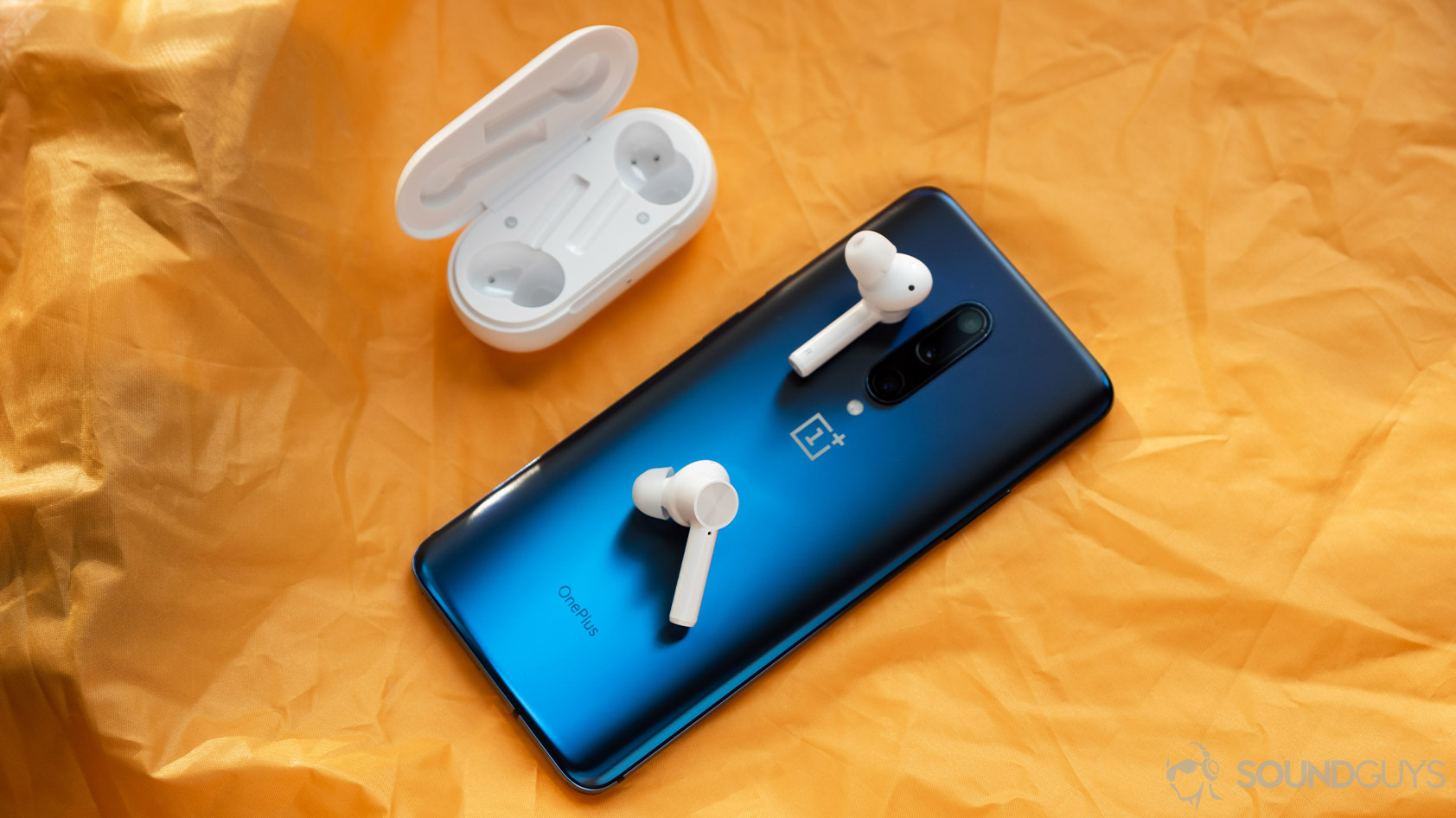 The OnePlus Buds Z cheap true wireless earbuds on top of a OnePlus 7 Pro smartphone in blue, with the open charging case off to the top left.