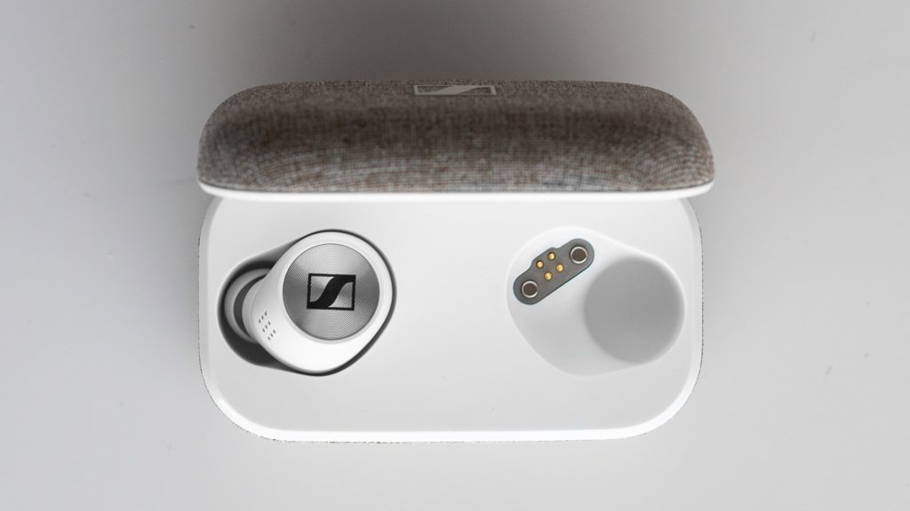 The Sennheiser Momentum True Wireless 2.0 sitting on a white table inside their case.