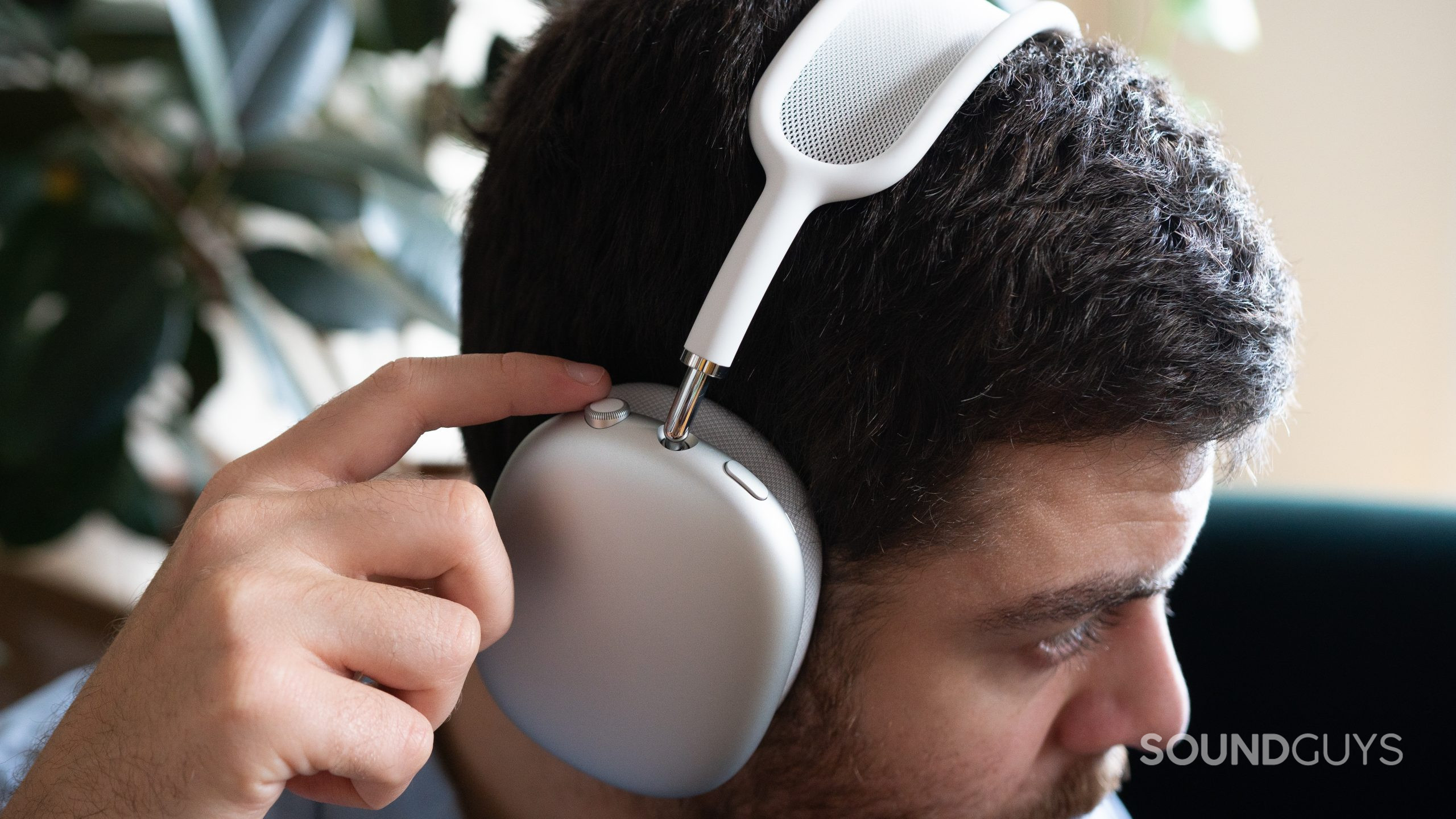 A man wears the Apple AirPods Max and adjusting volume via the digital crown.