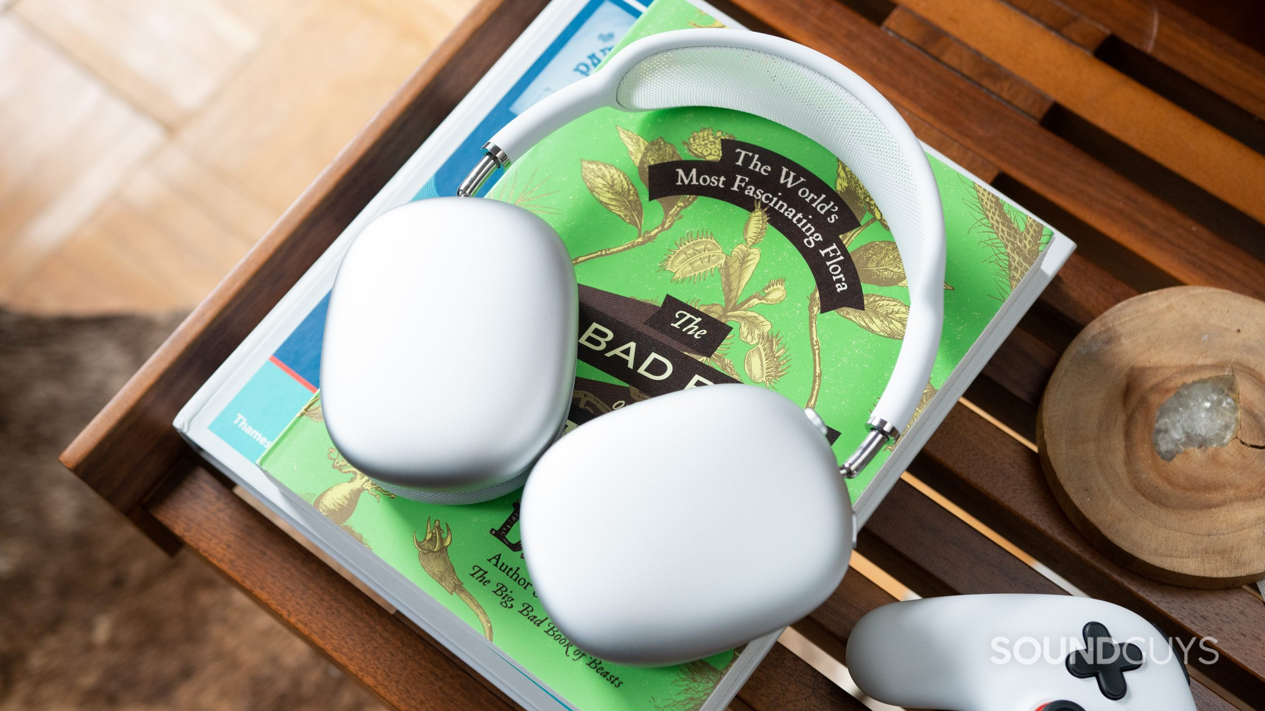 White Apple AirPods Max on top of a green book on a coffee table.