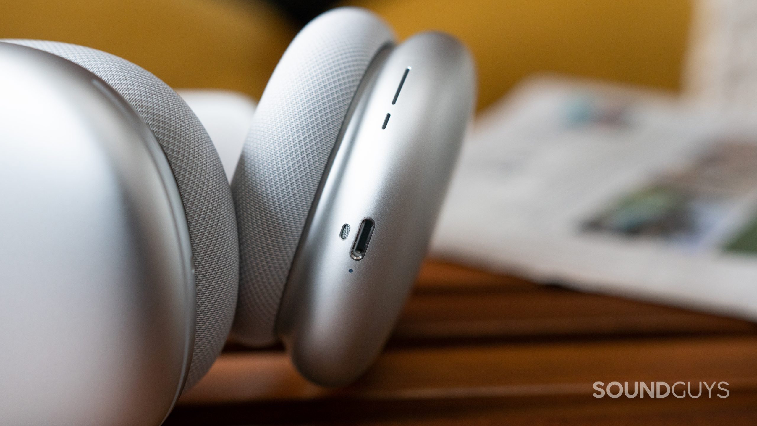 Close-up of the Lightning connector for the Apple AirPods Max as they lay next to a newspaper.