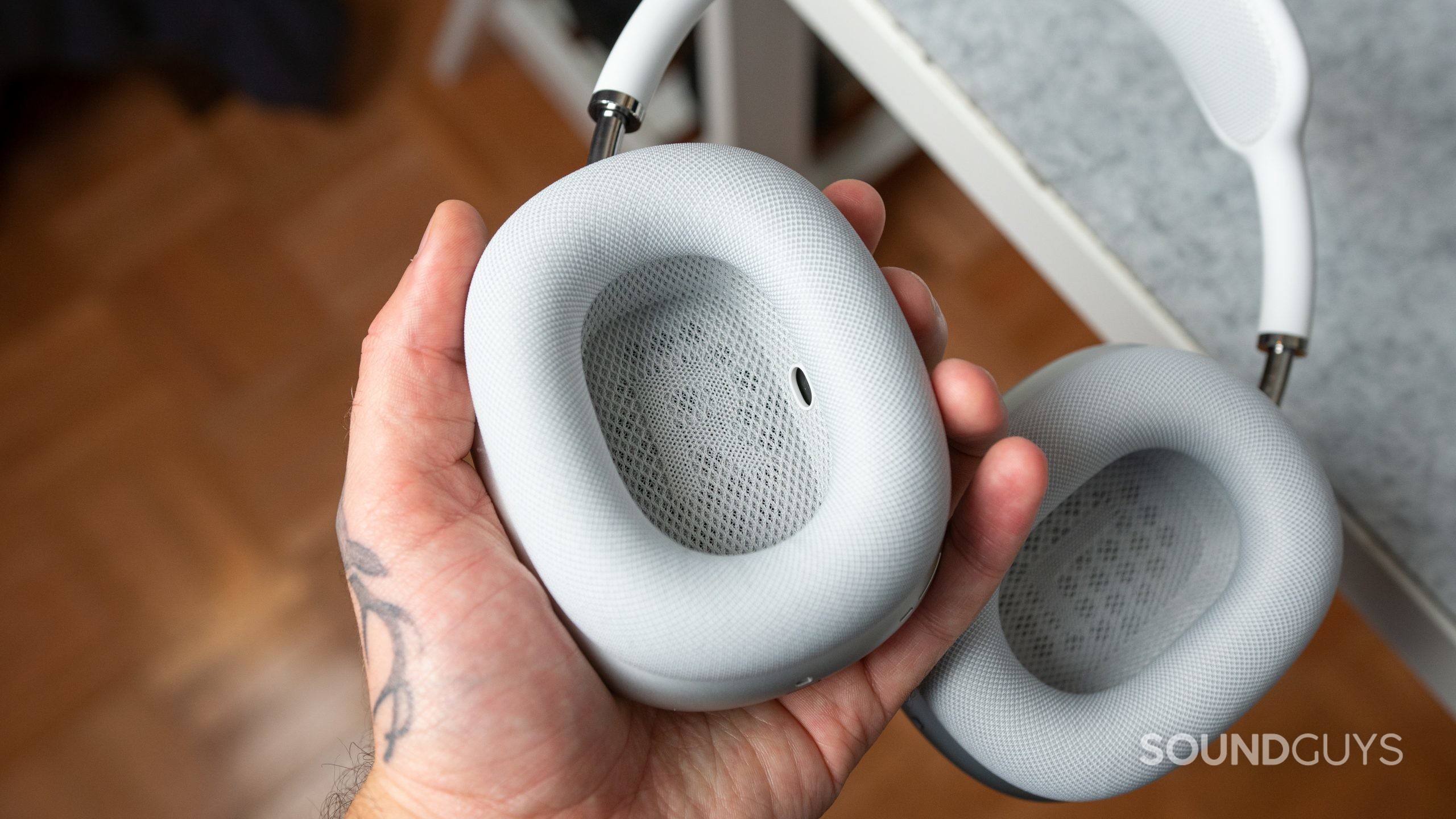 Man holding the Apple AirPods Max over a desk.