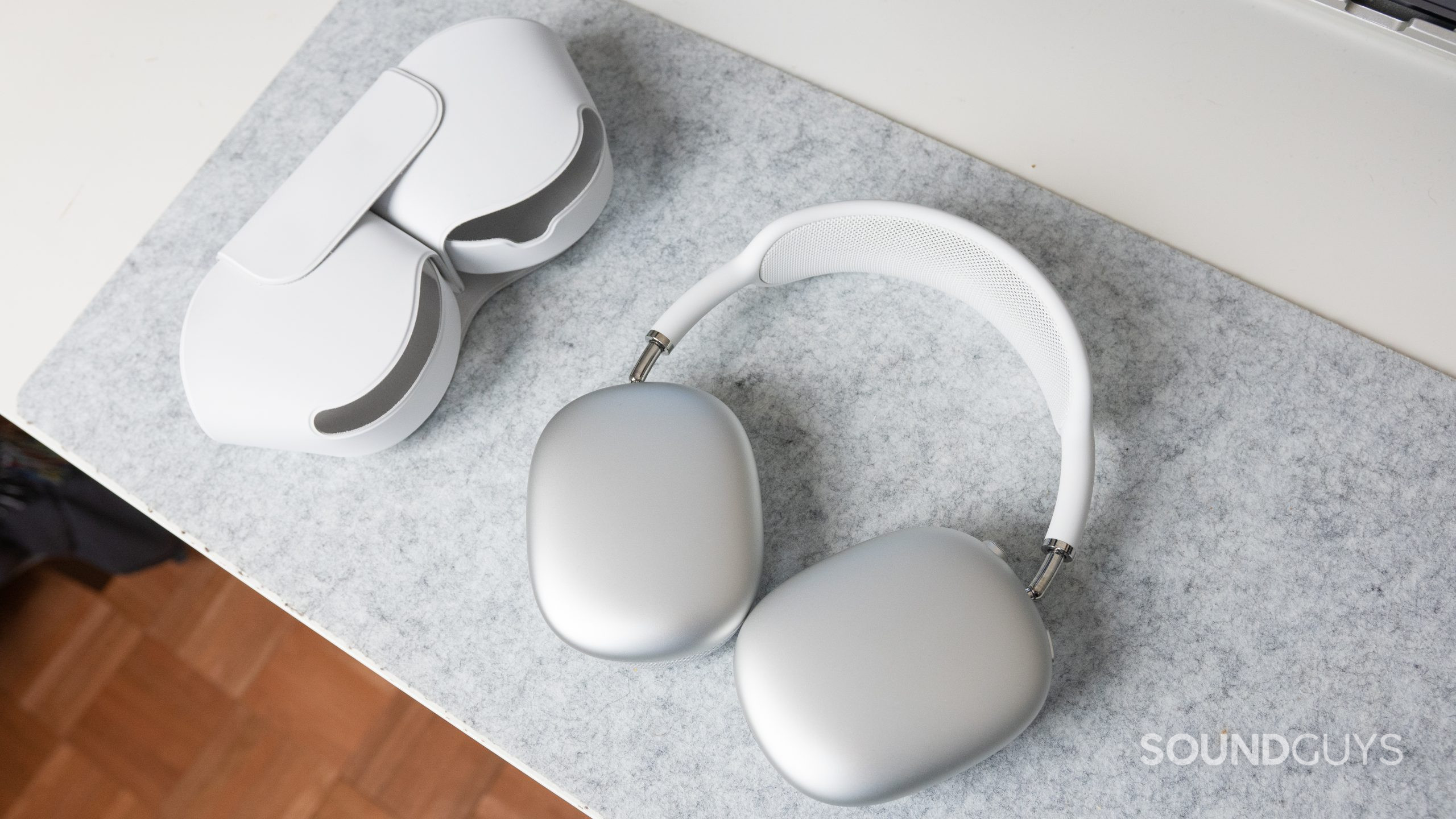 The Apple AirPods Max and its smart case on a white desk.