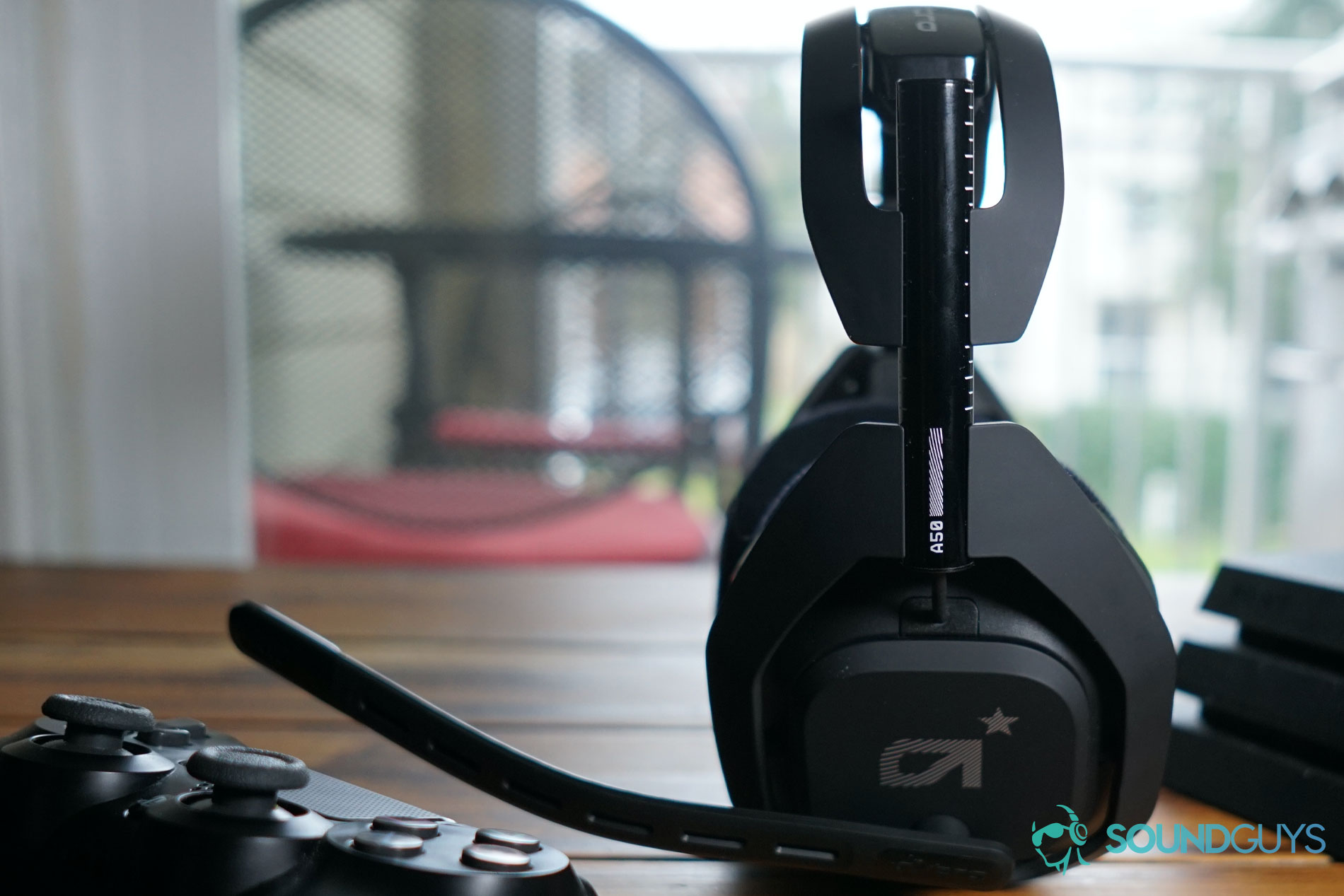 The Astro A50 Wireless sits between a dualshock controller and a Playstation 4 on a wooden coffee table.