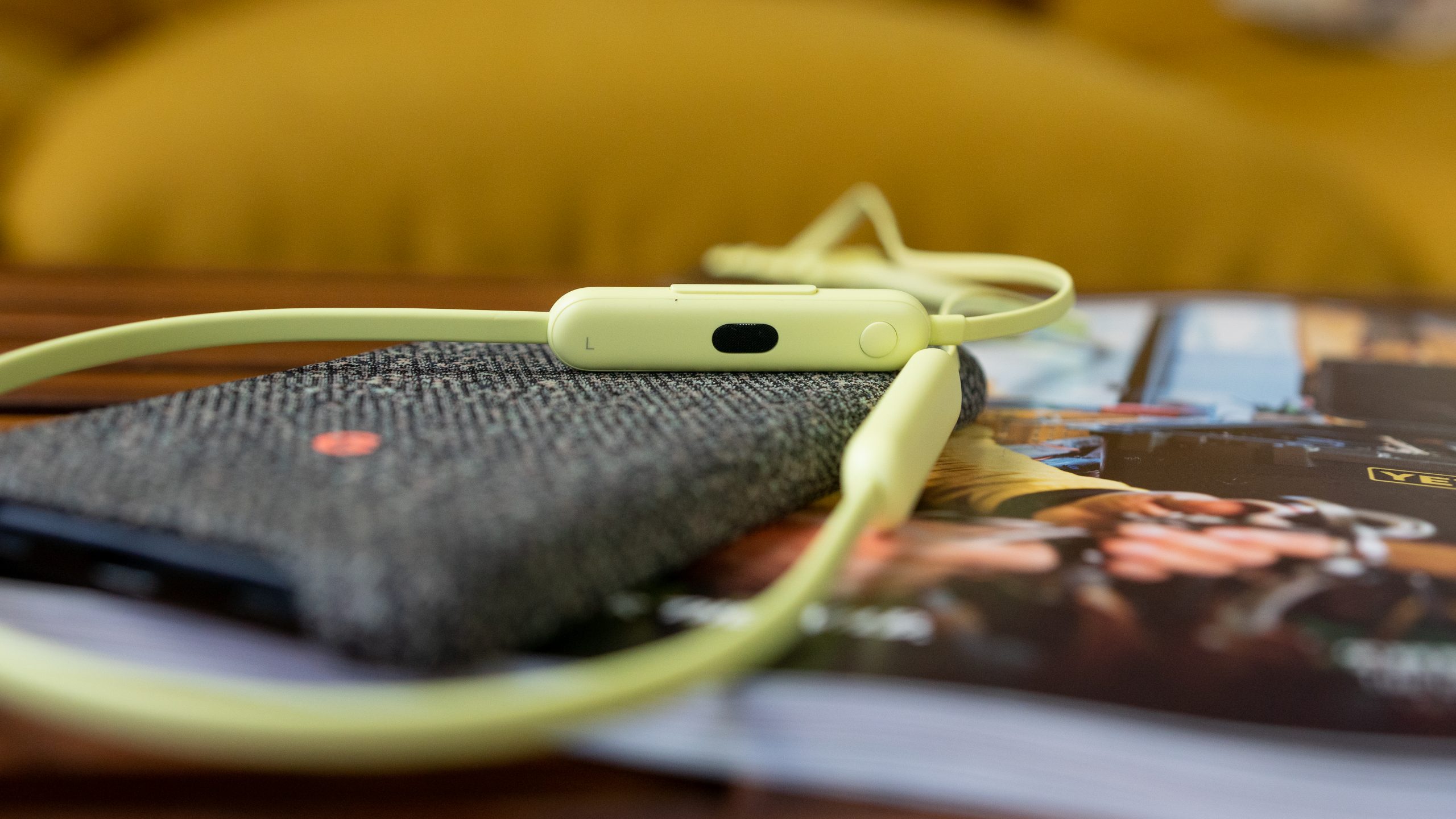 Yellow Beats Flex on top of a table with a magazine and a phone.