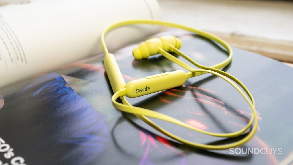 Beats Flex earbuds in yellow on an open magazine by the window.