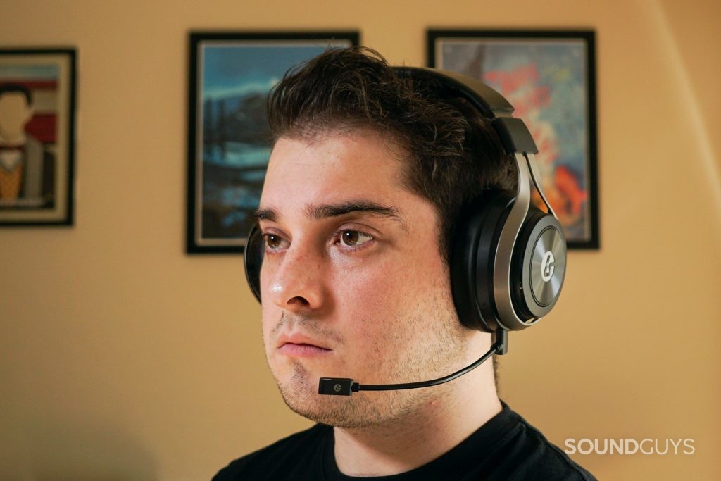 A man wears the LucidSound LS50X sitting at a computer with posters for Canada Heritage Minutes and My Brother, My Brother and Me in the background.