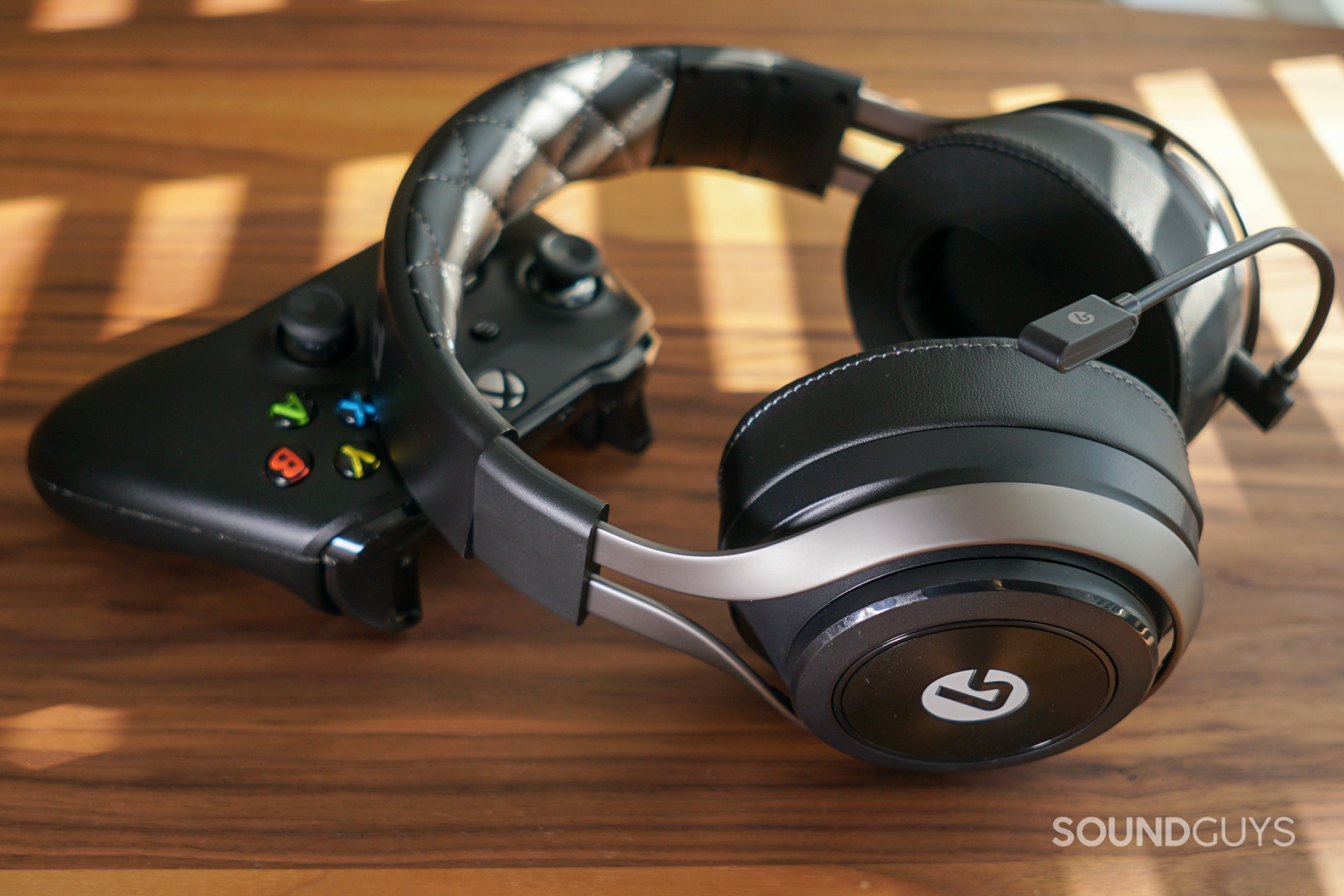 The LucidSound LS50X Leans on an Xbox One controller on a wooden table.