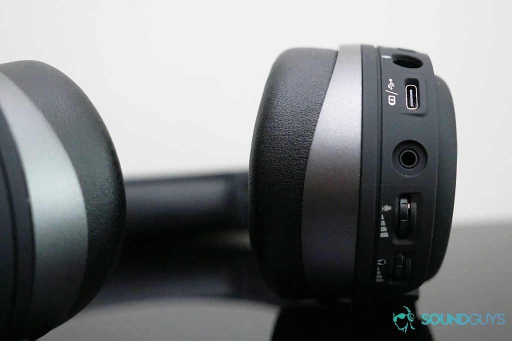 The HyperX Cloud Orbit S gaming headset lays on a black reflective surface with its USB-C, 3.5mm, and mic ports in view.