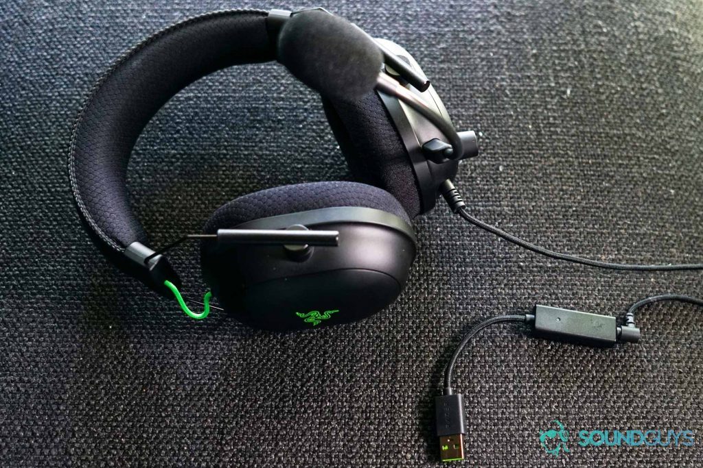 The Razer BlackShark V2 gaming headset sits on fabric surface with its USB sound card plugged in