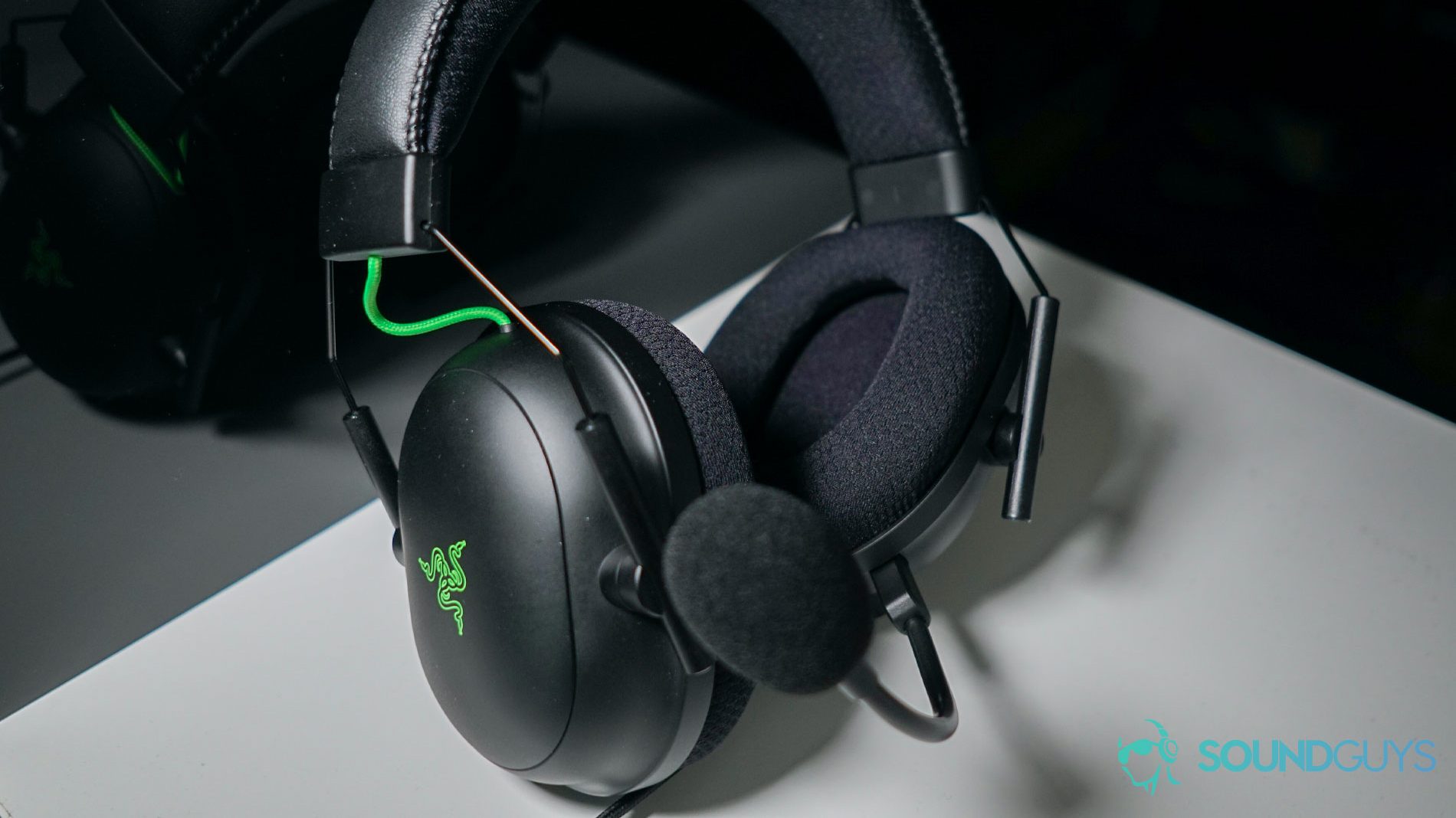 The Razer BlackShark V2 gaming headset sits in a white box in front of a reflective black surface