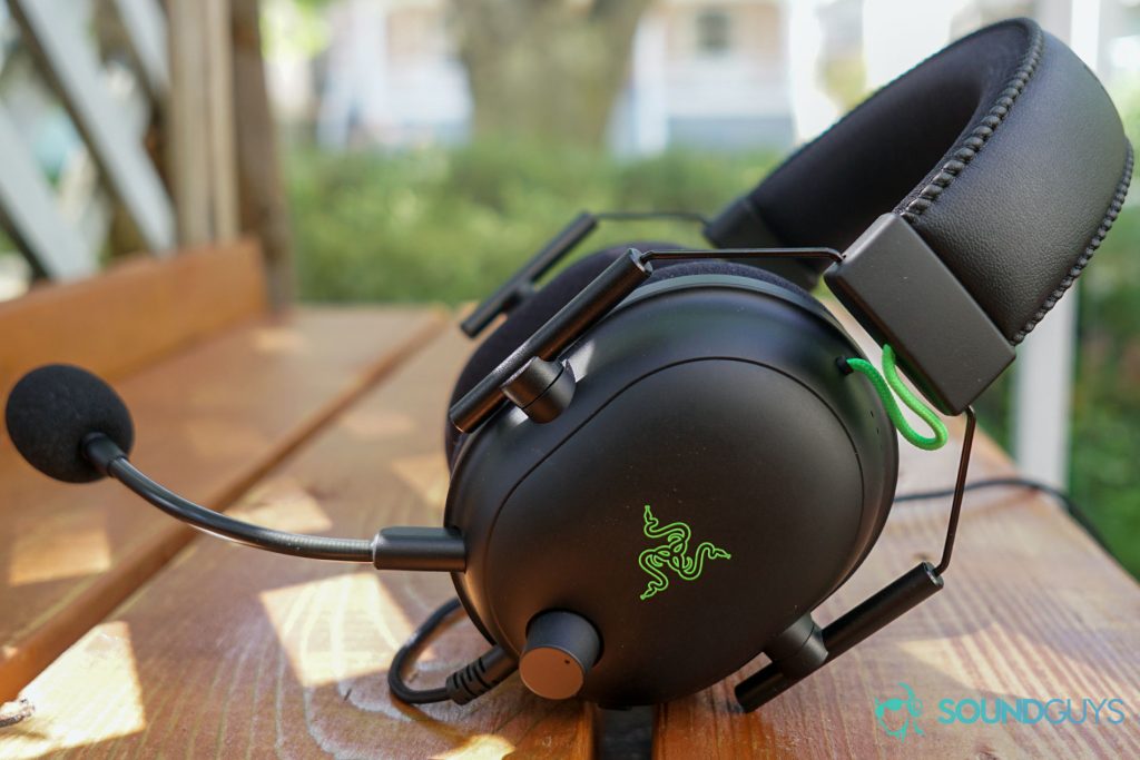 THe Razer BlackShark V2 gaming headset sits outside on a wooden table under a tree.