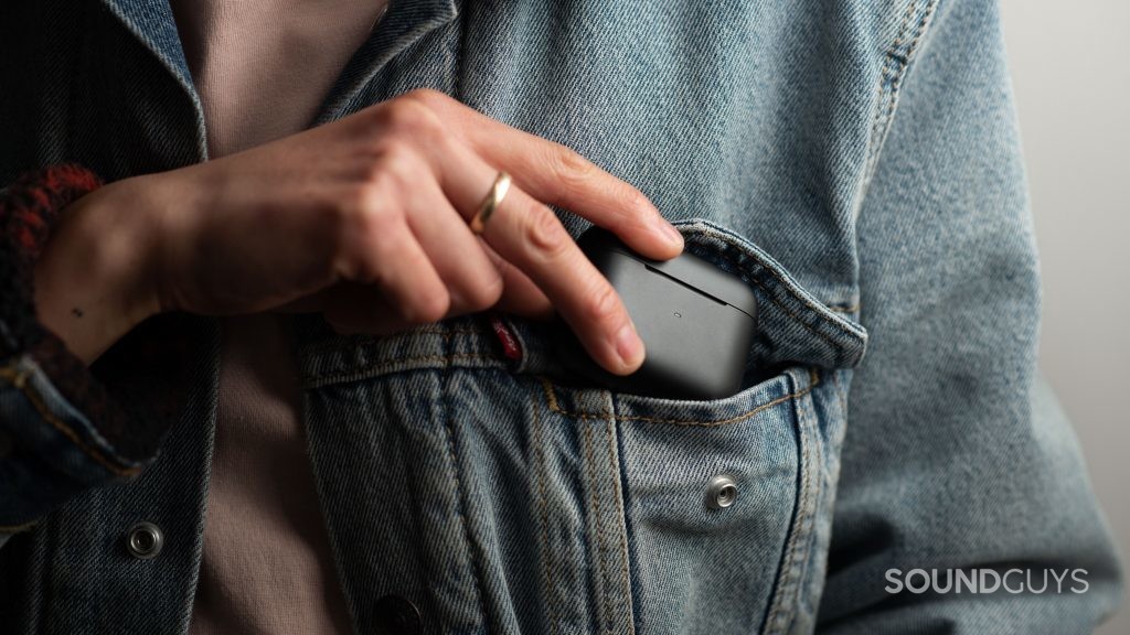 A woman places the Razer Hammerhead True Wireless Pro noise canceling earbuds case into a jacket pocket.