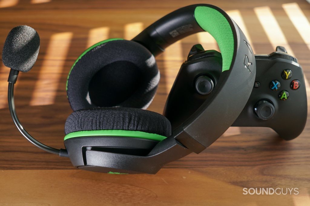 The Razer Kaira Wireless leans on an Xbox One controller on a wooden table near a window with the blinds drawn
