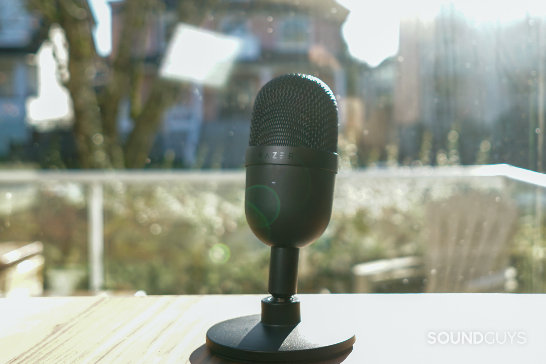 Razer Seiren Mini on a table in front of a window in the daytime.