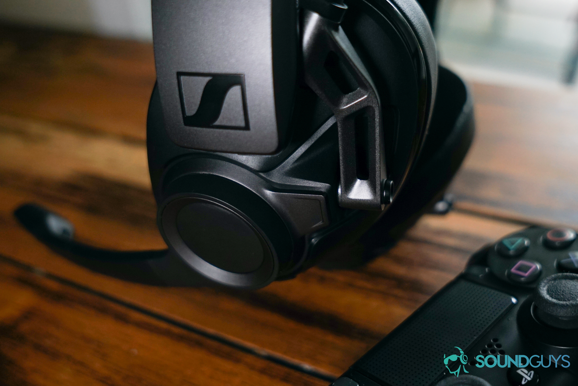 The Sennheiser GSP 670 gaming headset sits on a wooden table next to a Playstation 4 Dualshock controller.