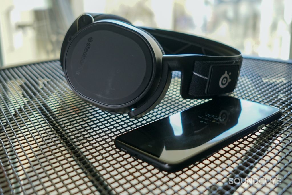 The SteelSeries Arctis 9 lays on a wire table behind a Google Pixel 4a