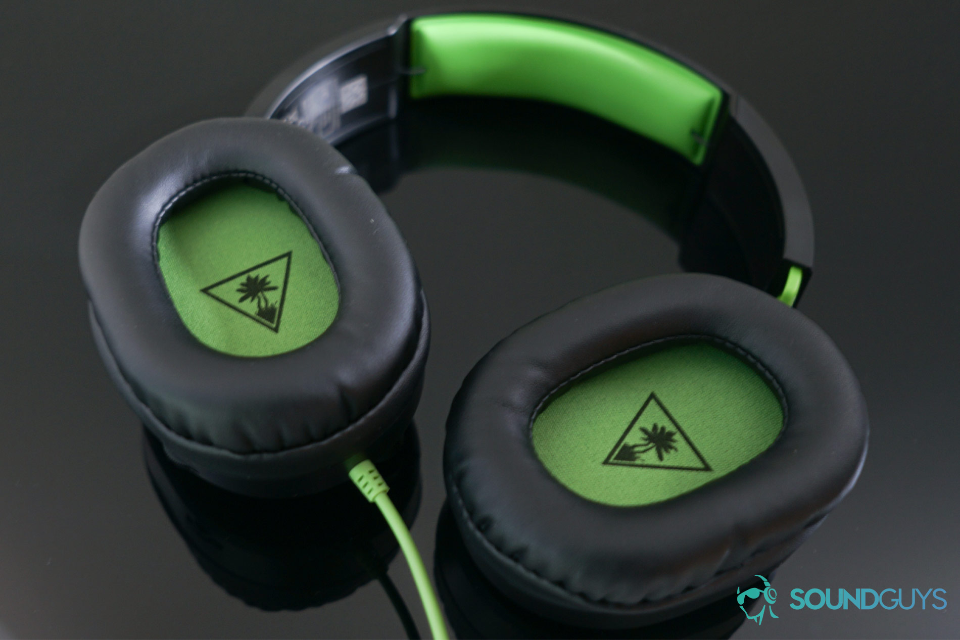 The Turtle Beach Recon 70 gaming headset's ear cups which are lined with a green material that matches the headband.