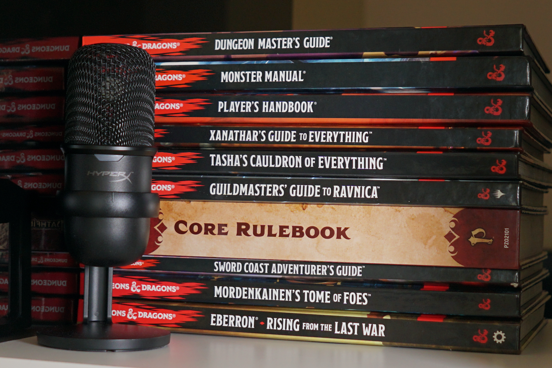 The HyperX Solocast stands on a shelf in front of the Dungeons and Dragons fifth edition Player's Handbook, Monster Manual, and more, as well as the Core Rulebook for Pathfinder second edition.