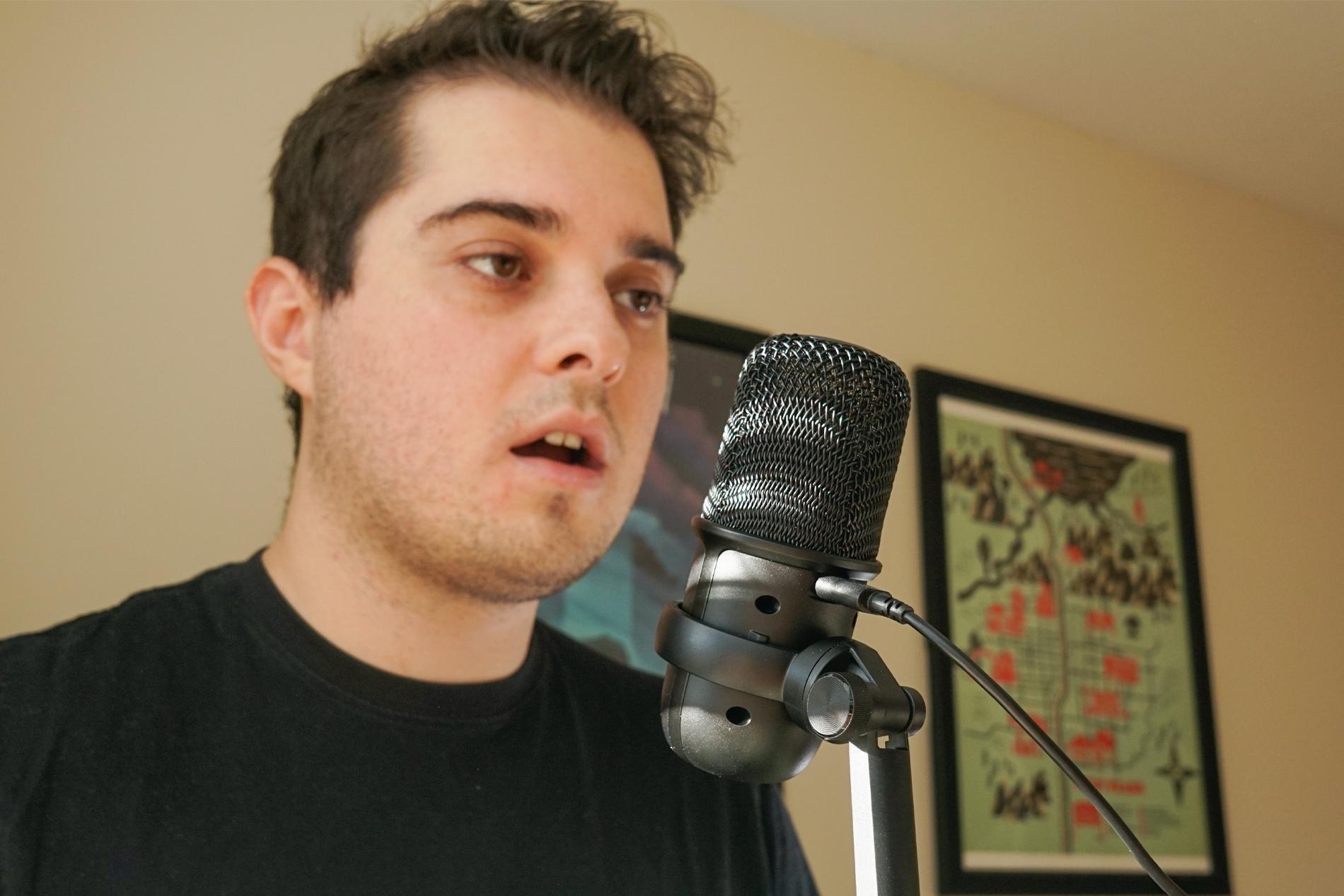 A man stands near the HyperX Solocast microphone, speaking into it.