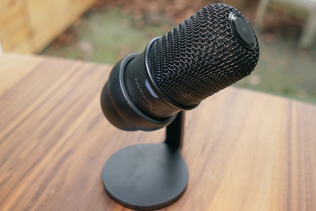 The HyperX Solocast is tilted in its stand on a wooden table