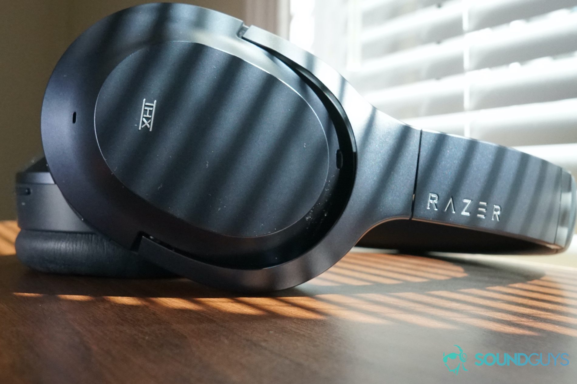 The Razer Opus sits on wooden surface by a window with the blinds down.