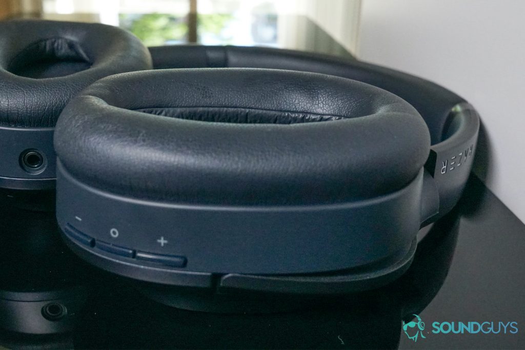 The Razer Opus lays on its front with its ear cups facing up on a black reflective surface with a window in the background