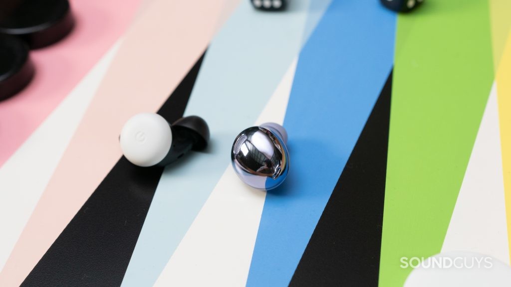 The Samsung Galaxy Buds Pro in violet on a gameboard next to a single Pixel Bud,