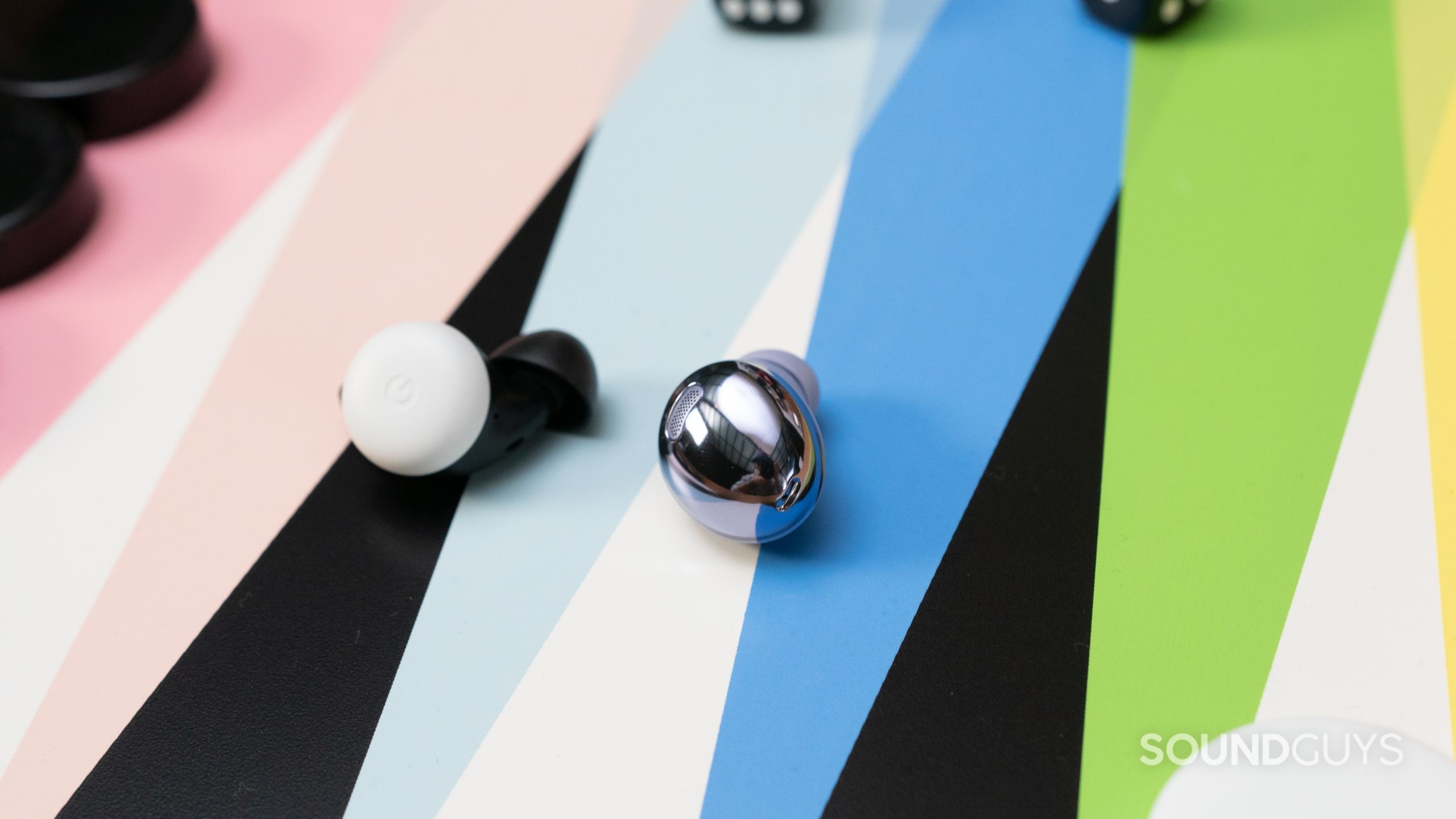 The Samsung Galaxy Buds Pro in violet on a gameboard next to a single Pixel Bud,
