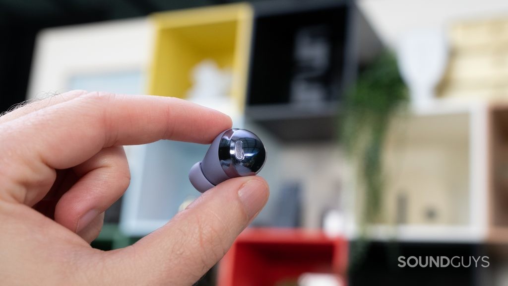 The glossy back of the Samsung Galaxy Buds Pro in focus as man holds it up.