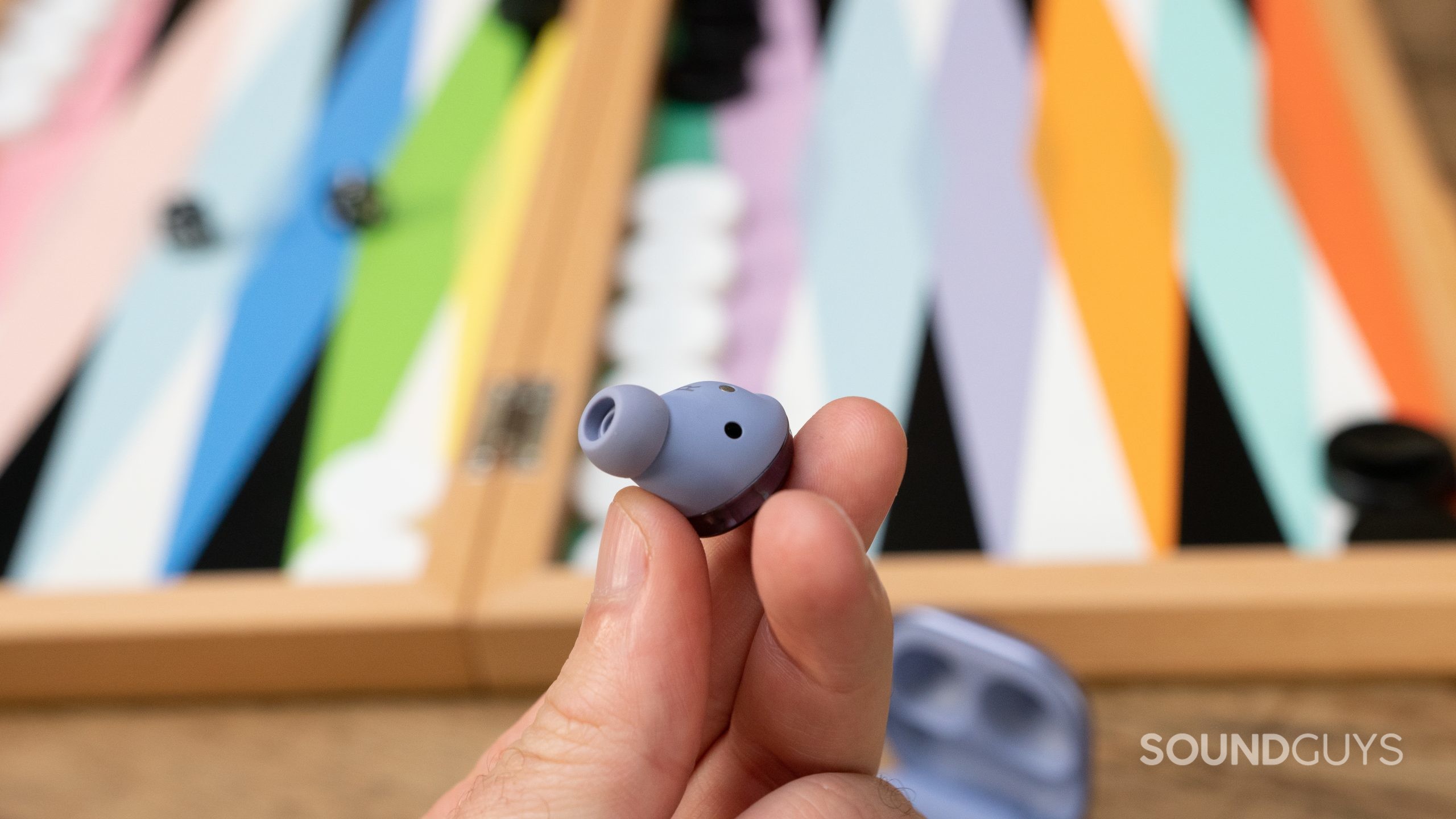 Man holding Samsung Galaxy Buds Pro earbud with focus on proximity sensor.