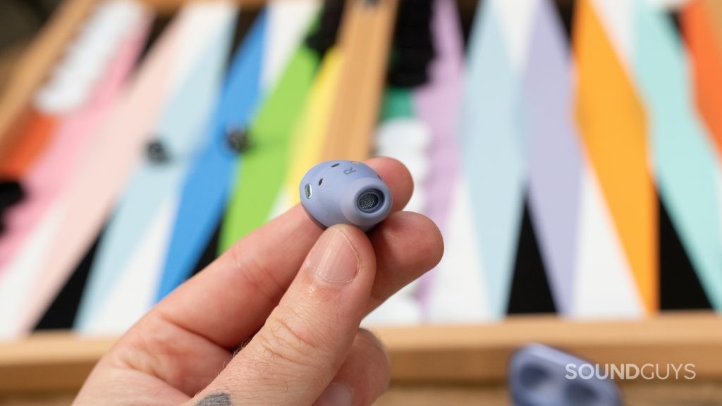 A single Samsung Galaxy Buds Pro earbud in hand over a game.