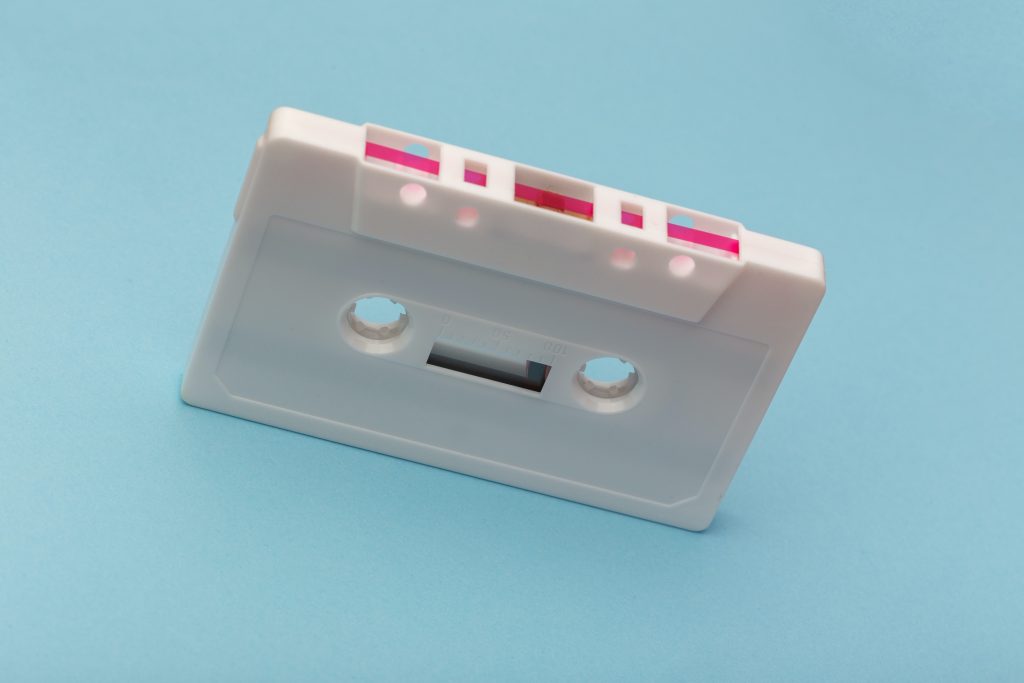 A white cassette tape against a light blue background.